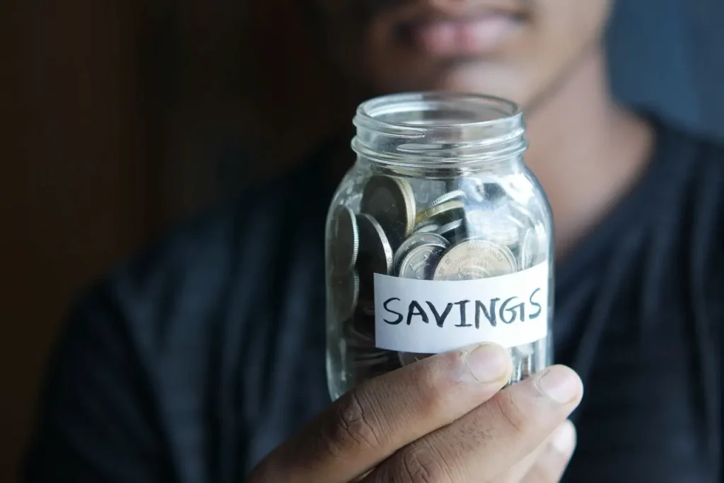 A Person Holding a Jar of Coins Labelled Savings