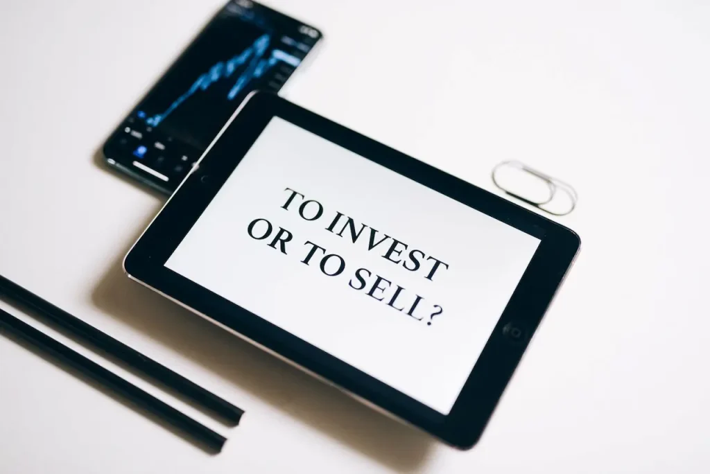 A Tablet Displaying the Text To Invest or To Sell 