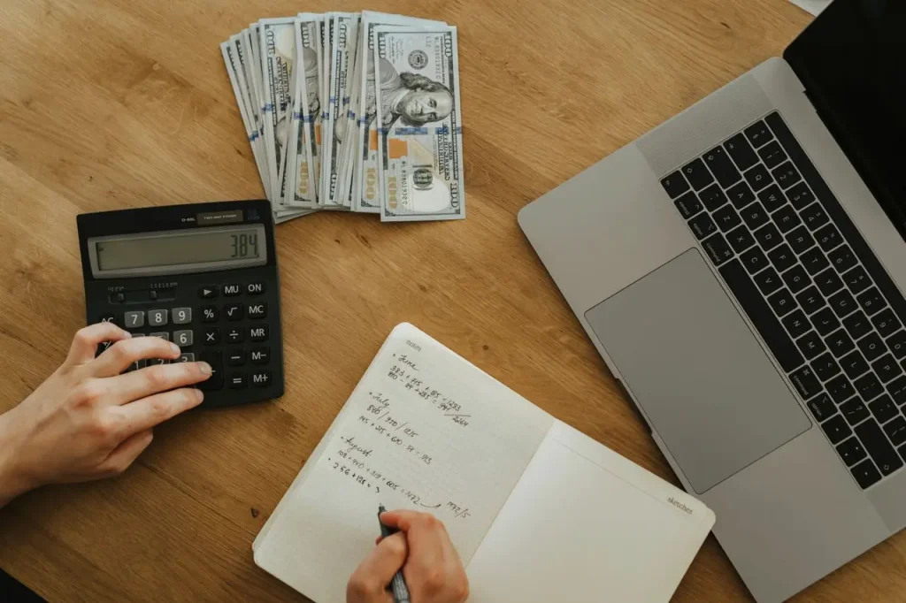 Person Working on a Budget at a Laptop with a Calculator